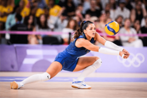 "Jogador líbero de vôlei com camisa amarela defendendo bola em quadra profissional"